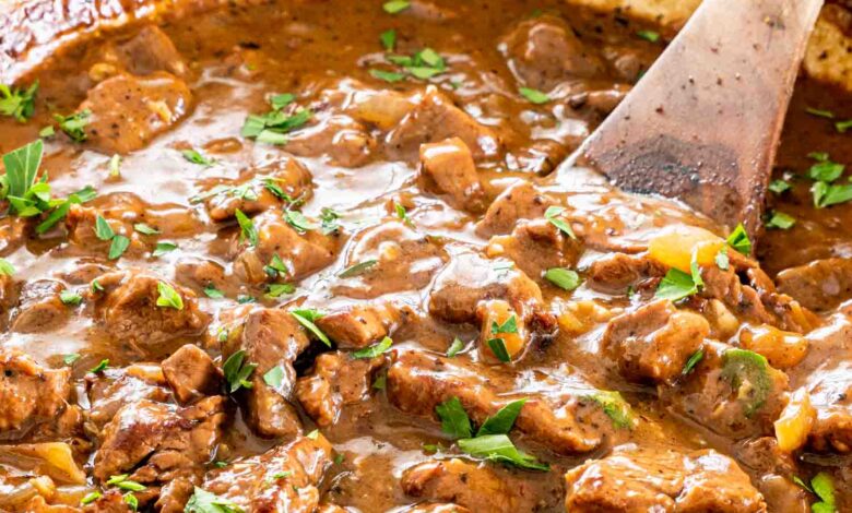 beef tips with gravy in a braiser garnished with parsley.