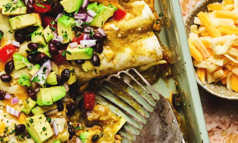 spatula dishing up black bean enchiladas from baking dish