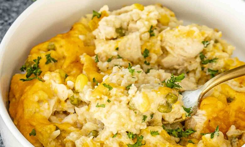 a serving of chicken and rice casserole in a white bowl with a golden fork inside.