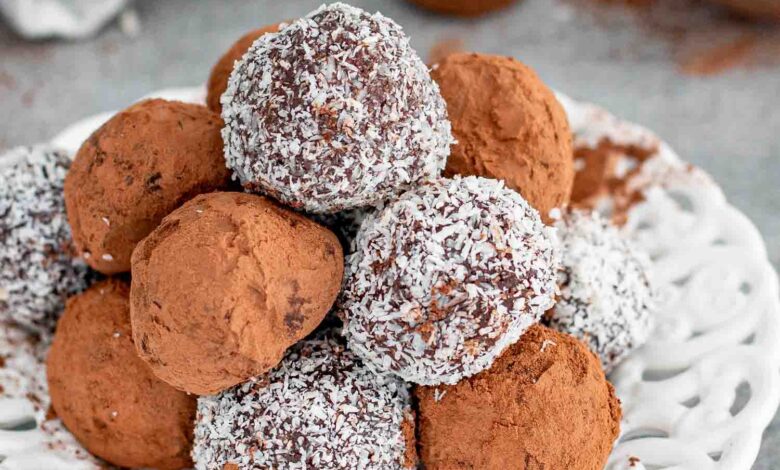 a few chocolate truffles on a plate, some with cocoa powder and some with coconut.