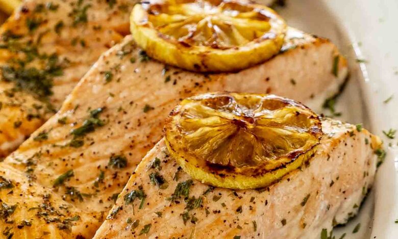 baked salmon with lemon slices on a white platter.