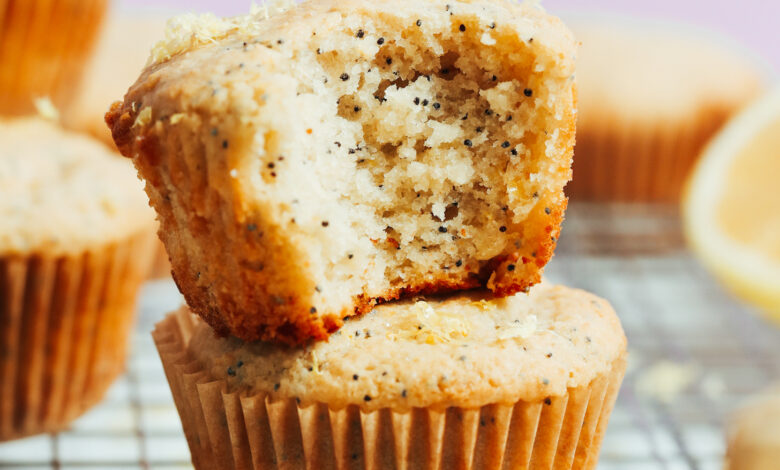 Stack of vegan gluten-free lemon poppy seed muffins with the inner texture showing where a bite was taken out of one muffin