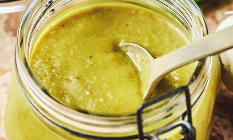 spoon dipping into green enchilada sauce in jar