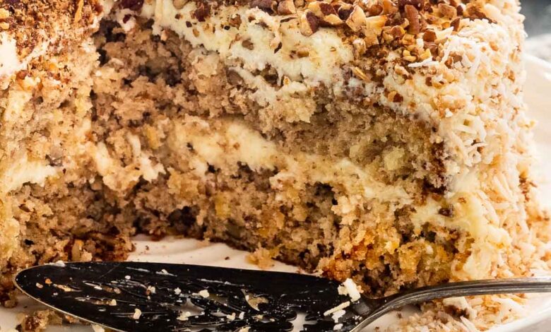 picture of hummingbird cake on a white cake platter with a couple slices cut out.