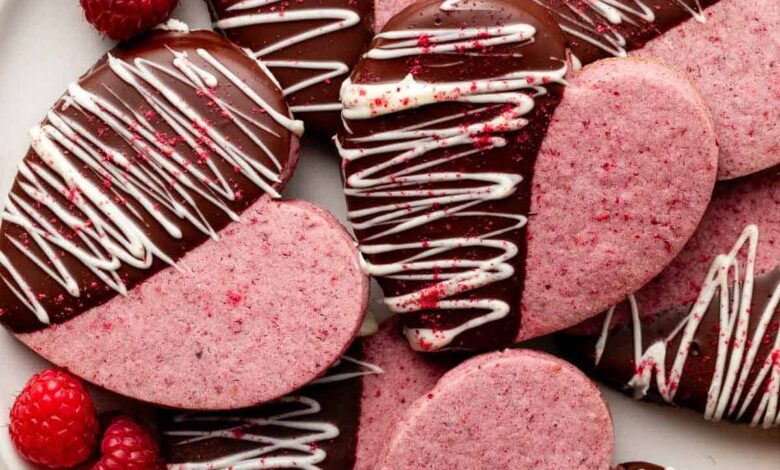 heart-shaped raspberry sugar cookies dipped in chocolate and white chocolate on white plate.