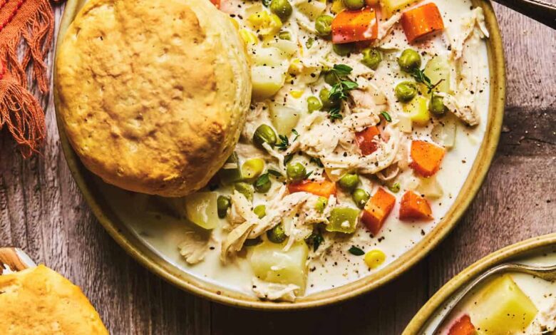 chicken soup with vegetables and biscuit in bowl on table